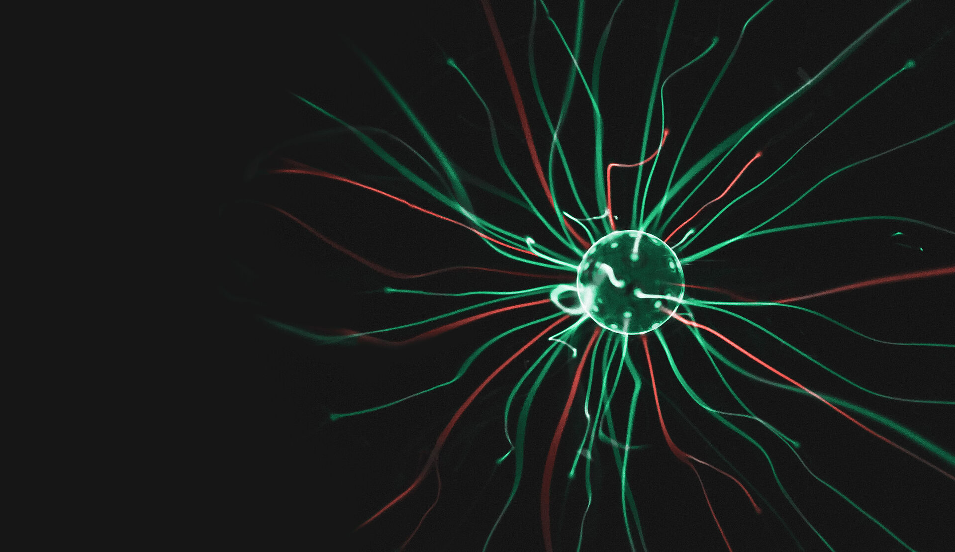 Abstract representation of a glowing sphere with green and red lines of light radiating outward, symbolizing energy or data streams.